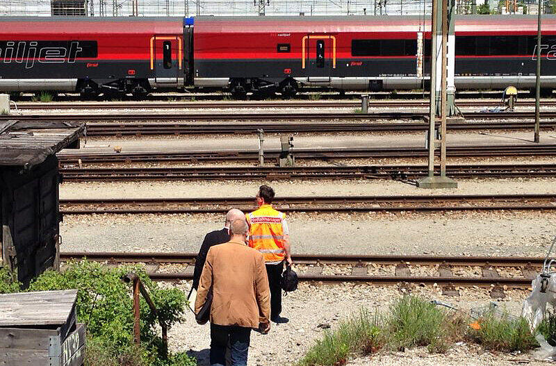Ein Bahnarbeiter führt zwei Kriminalpolizisten zum Railjet, in dem das Neugeborene getötet wurde.