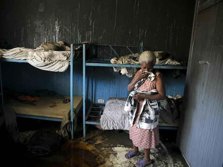 Eine Mitarbeiterin des von Flammen verwüsteten Waisenhauses steht in einem Schlafzimmer.