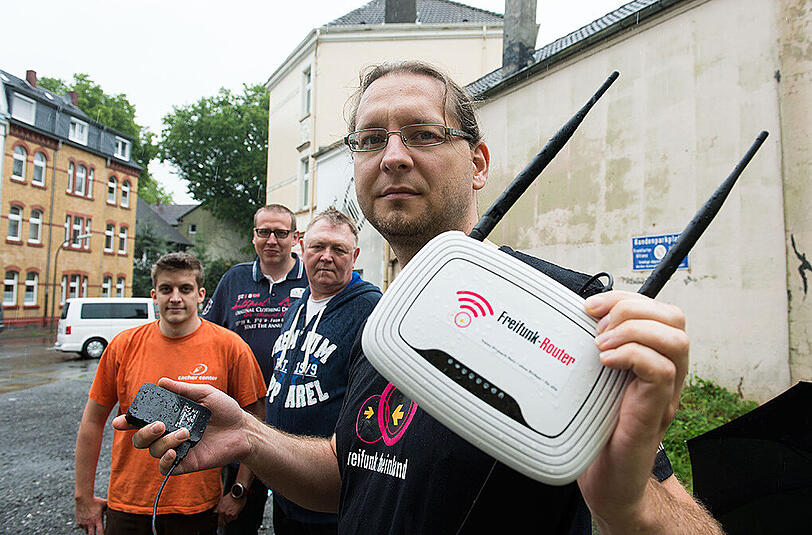 Sven Borchert, Michael Thiesbrummel, Holger Dieckmann und Tim Friedrich (r-l) von der Initative "Freifunk" mit einem batteriebetriebenen W-LAN Router auf einem Parkplatz in Dortmund, auf dem häufig Bewohner eines nahe gelegenen Asylantenwohnheims ihr freies Internet verwenden.