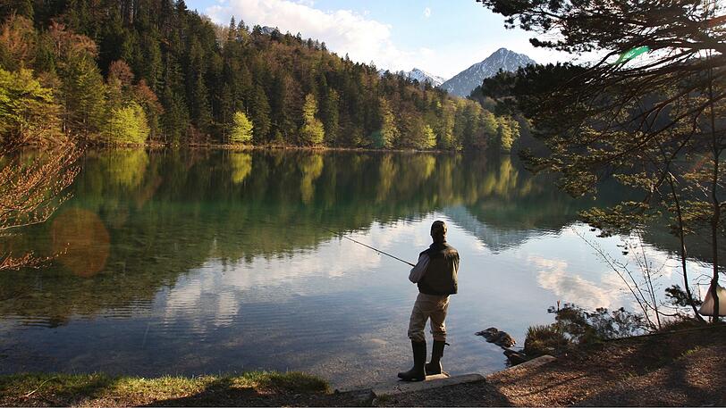 Angler am klaren Wasser des Alatsees bei Füssen.