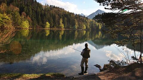 Angler am klaren Wasser des Alatsees bei Füssen.