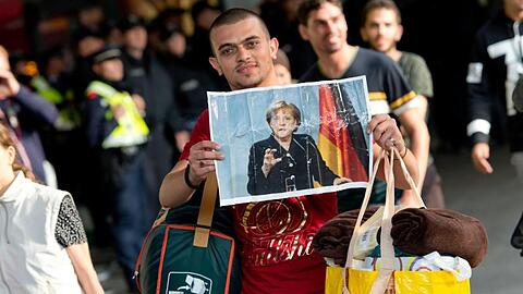 Ein Flüchtling, der kurz zuvor mit einem Zug angekommen ist, hält voller Hoffnung ein Foto von Angela Merkel in den Händen.(Archiv).
