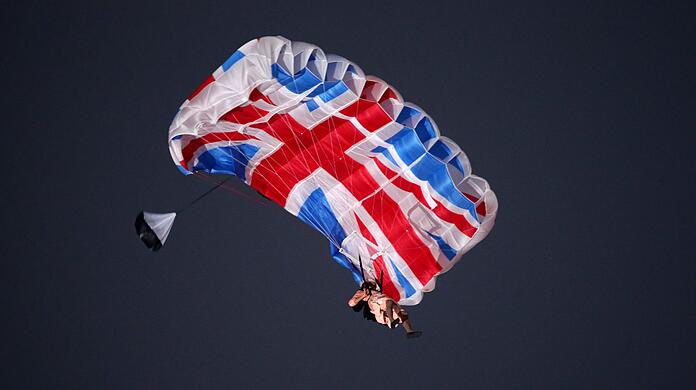 Ein Schauspieler, verkleidet als britische Königin Elizabeth II., schwebt bei der Eröffnungsfeier der Olympischen Spiele in London mit einem Fallschirm ein. Ein Schauspieler, verkleidet als britische Königin Elizabeth II., schwebt bei der Eröffnungsfeier der Olympischen Spiele in London mit einem Fallschirm ein.