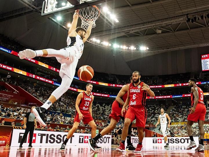 Maximilian Kleber (l) hängt nach einem Dunking am Korb.
