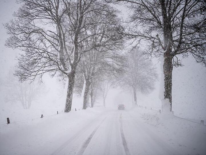 Ein Auto fährt über eine Schnee verwehte Landstraße. Foto: Lino Mirgeler/Archiv