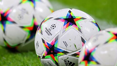 Fußbälle mit dem Logo der Champions League liegen auf dem Rasen.