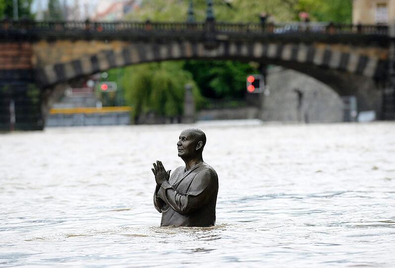 Da hilft nur noch beten: Eine Statue im tschechischen Prag steht bis zur Hüfte im Wasser.