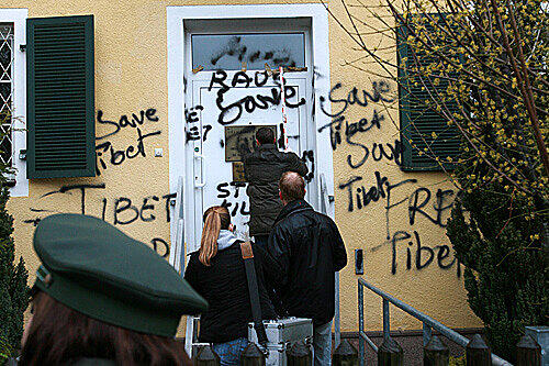 Polizeibeamte der Spurensicherung vermessen Graffiti, die am Montag an der Eingangstür des chinesischen Generalkonsulats in München zu sehen sind.