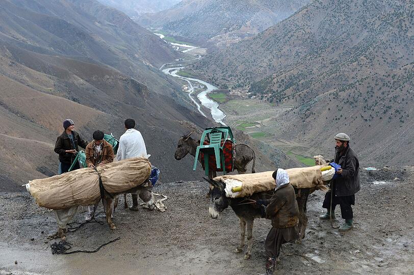 Afghanische Männer beladen Esel mit Wahlunterlagen für den Transport durch das Panjshir Tal.