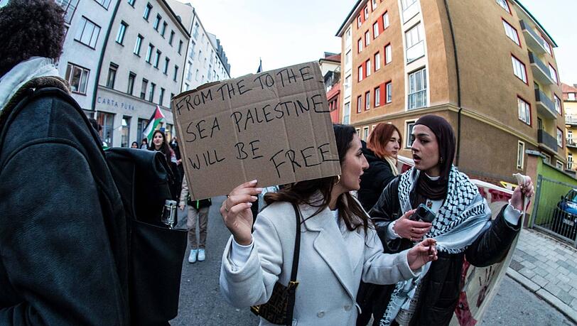 Bei einer Demo im Dezember in München hält eine Frau ein Schild mit dem verbotenen Slogan: "Vom Fluss bis zum Meer".