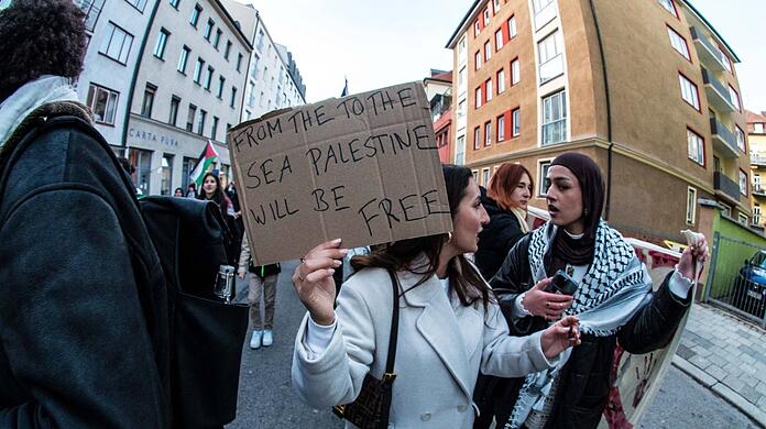 Bei einer Demo im Dezember in München hält eine Frau ein Schild mit dem verbotenen Slogan: "Vom Fluss bis zum Meer".