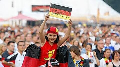 &bdquo;Danke!&ldquo; Auch wenn es die Fußballer im fernen Afrika am Samstag nicht sehen konnte: Celina (9) bedankte sich auf den Schultern von Klaus Knorr mit einem selbstgebastelten Schild für den 3:2-Sieg des deutschen Teams gegen Uruguay.
