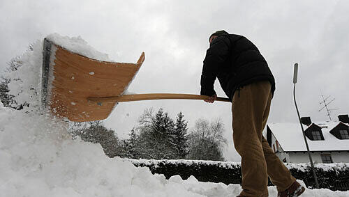 Ein Hausbesitzer beim Schneeschaufeln