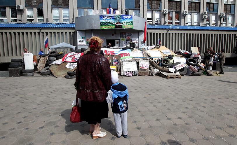 Eine Frau und ein Kind stehen in Lugansk, Ukraine vor einem von prorussischen Aktivisten besetzten Gebäube.