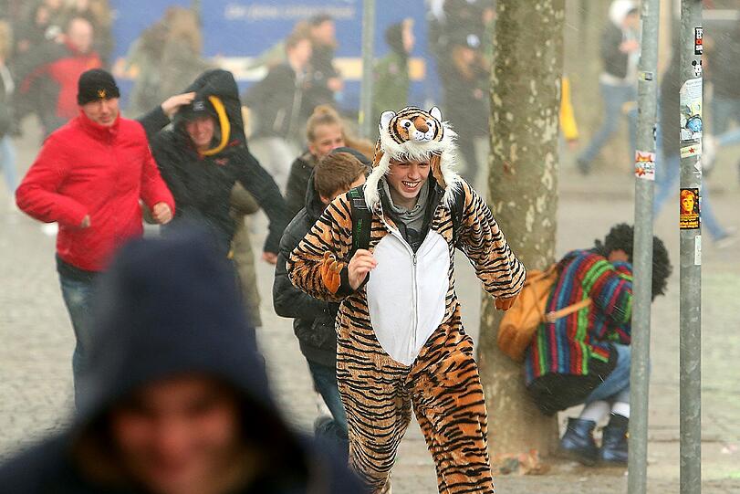 Narren flüchten am Rosenmontag in Düsseldorf vor Regen und Sturm.