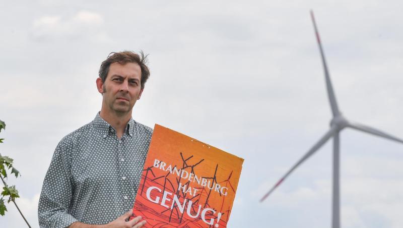 Eigenheimbesitzer Stefan Hellert auf seinem Grundstück. In rund 1500 Metern Entfernung dreht sich der Rotor einer Windenergieanlage. Eigenheimbesitzer Stefan Hellert auf seinem Grundstück. In rund 1500 Metern Entfernung dreht sich der Rotor einer Windenergieanlage.