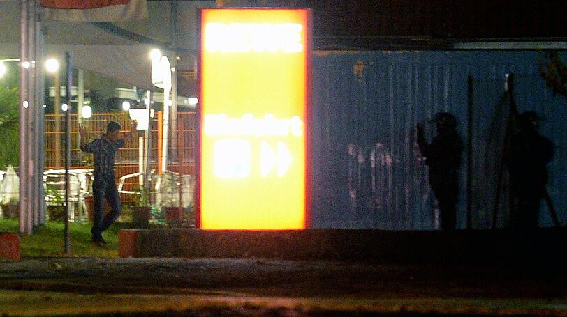 Mit erhobenen Händen kommt ein Mann auf die SEK-Beamten zu, im Hintergrund lauern Heckenschützen der Polizei. Die Beamten nehmen den Mann fest, es ist aber nicht der Täter, der sich in einem Imbiss in Freiburg veschanzt hat.