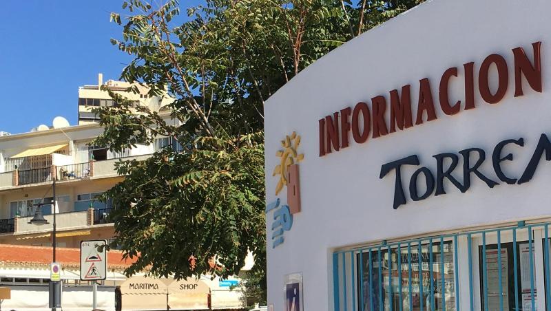 Touristen gehen an der Strandpromenade neben einem Touristeninformationsbüro in Torremolinos entlang. Touristen gehen an der Strandpromenade neben einem Touristeninformationsbüro in Torremolinos entlang.