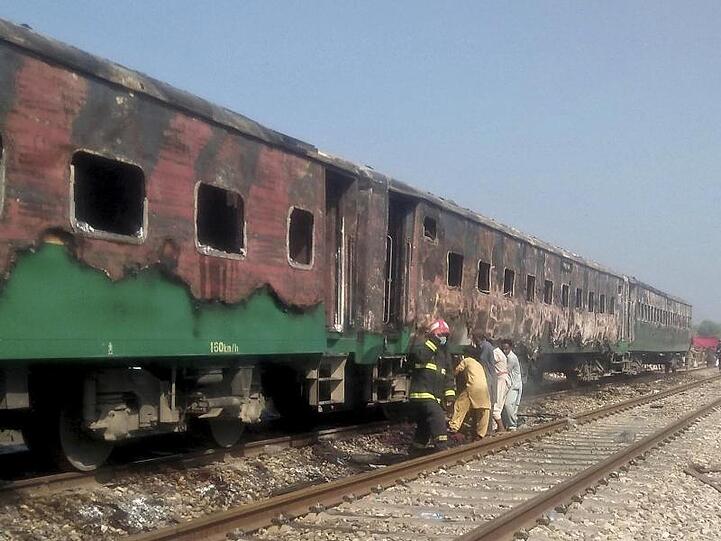 Pakistanische Beamte untersuchen den Zug nach dem Brand.