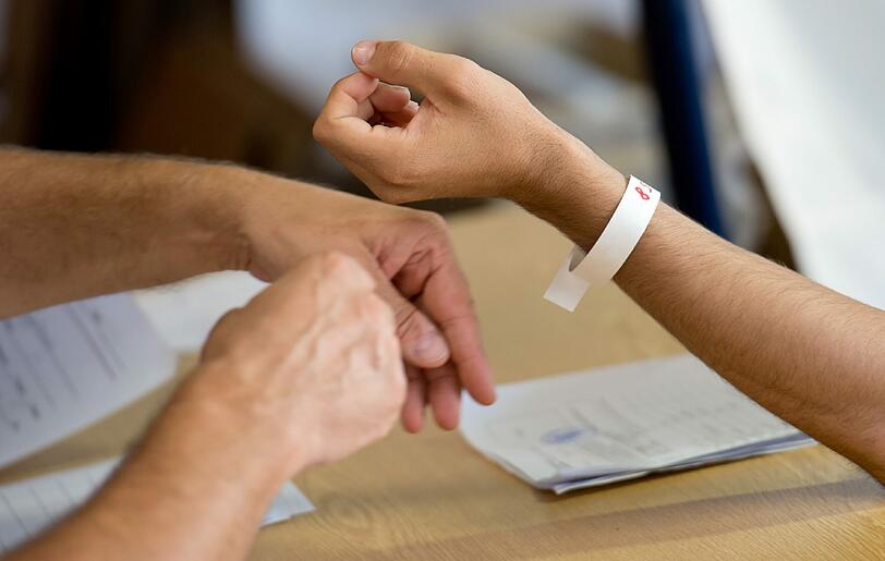 Ein Flüchtling bekommt in einer Registrierungsstelle für Flüchtlinge von einem Bundespolizisten ein Armband mit einer Nummer. Um der Flüchtlingswelle Herr zu werden, bekommt Bayern vom Bund 100 zusätzliche Bundespolizisten gestellt.