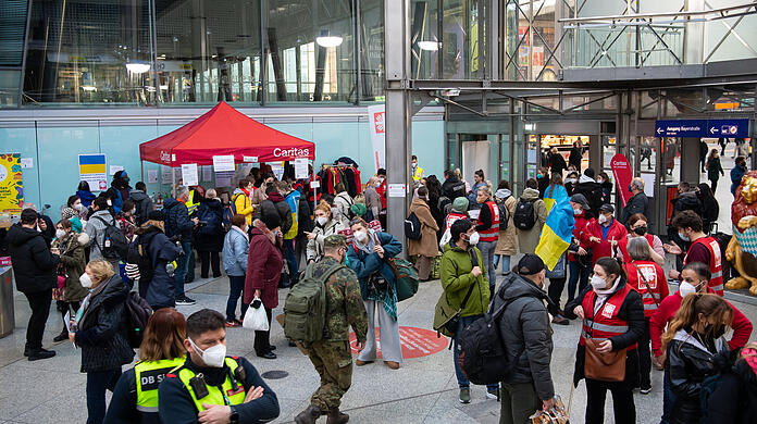 Flüchtlinge aus der Ukraine werden nach ihrer Ankunft am Hauptbahnhof von Mitarbeitern der Caritas und freiwilligen Helfern empfangen.