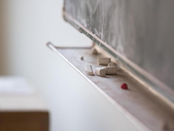 Kreide liegt unter einer Tafel in einem Klassenzimmer. Foto: Fabian Sommer/Archivbild