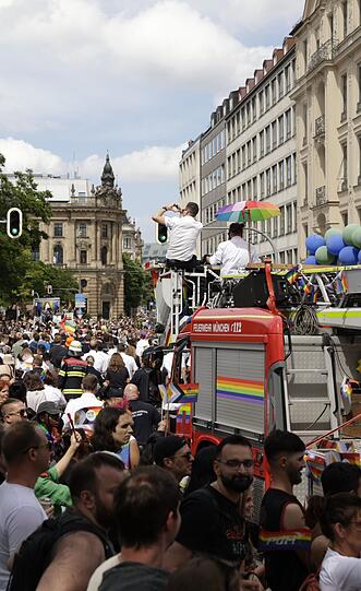 Fröhlich feiernde Teilnehmer bei der CSD-Parade in München, auch die Feuerwehr war mit dabei.