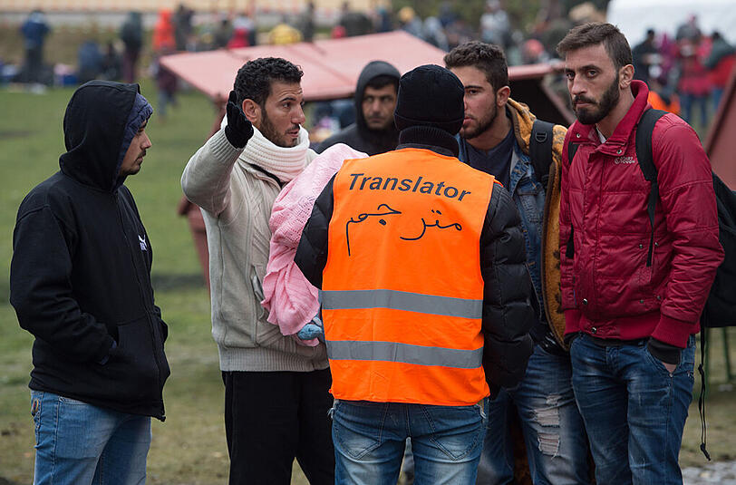 Ein Übersetzer mit einer Weste mit der Aufschrift "Translator" spricht am 29.10.2015 nahe Wegscheid an der deutsch-österreichischen Grenze mit Flüchtlingen aus verschiedenen Herkunftsländern.