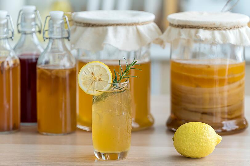 R&uuml;hren Sie 100 Gramm Rohrohrzucker in den hei&szlig;en Tee und f&uuml;gen Sie einen Liter kaltes Wasser hinzu, damit der Tee auf etwa 25 Grad abk&uuml;hlt. Erst dann kommt der SCOBY mit etwas Kombucha-Ansatzfl&uuml;ssigkeit dazu. Stellen Sie das Gef&auml;&szlig; an einen dunklen Ort mit guter Luftzirkulation. Nach rund f&uuml;nf Tagen ist der Kombucha fertig und kann in dunkle Flaschen gef&uuml;llt und fest verschlossen werden. Danach ab in den K&uuml;hlschrank.