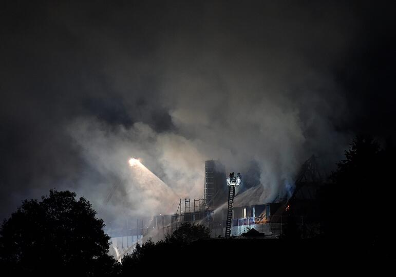 Feuerwehrleute löschen im Bereich des Klosters Rottenbuch den Dachstuhl eines Gebäudes, der in voller Ausdehnung brennt.