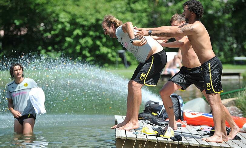 Dortmunds Patrick Owomoyela (r.) und Kevin Grosskreutz (2.v.r.)geben ihrem Coach einen kräftigen Schubs ins Wasser.