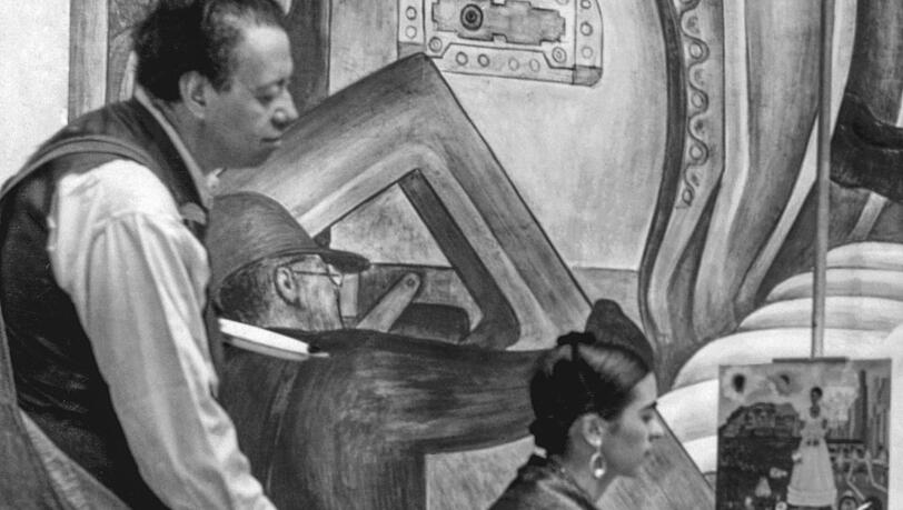 Diego Rivera (vor einem typischen Wandbild) blickt Frida 1932 am Detroit Institute of Arts über die Schulter. Diego Rivera (vor einem typischen Wandbild) blickt Frida 1932 am Detroit Institute of Arts über die Schulter.