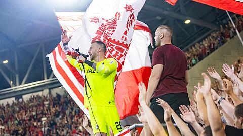 Freiburgs Torwart Mark Flekken feiert nach dem Spiel mit den Fans auf dem Zaun den Sieg.