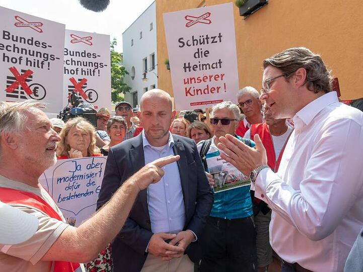 Bundesverkehrsminister Andreas Scheuer (CSU) unterhält sich mit demonstrierenden Anwohnern der Region Rosenheim. Foto: Peter Kneffel