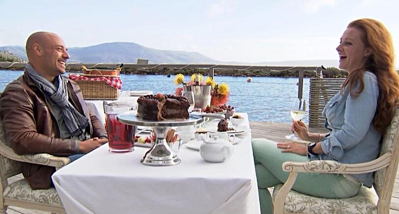 Christian und Nena verstehen sich prächtig bei Kuchen und Sekt auf einem Steg am See.