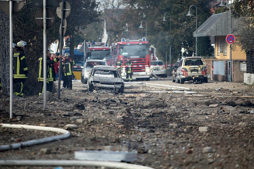 Die Wracks der bei der Explosion zerstörten Autos stehen am Straßenrand.