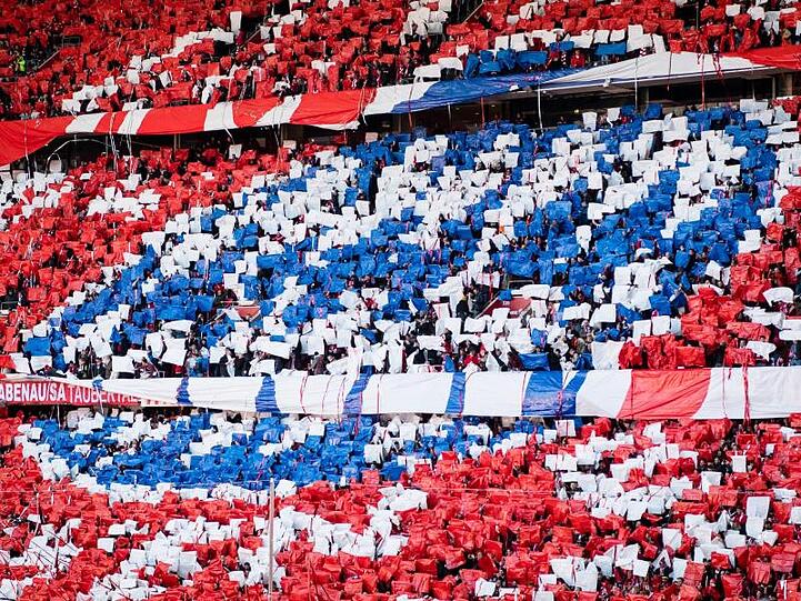Die Fans von Bayern München halten während einer Choreographie blaue, weiße und rote Zettel hoch. Foto: Matthias Balk/dpa/Archivbild
