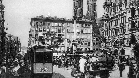 Menschen sehen sich das Glockenspiel am Marienplatz an. Auch Straßenbahnen sind hier damals noch gefahren. Klicken Sie sich in der Bilderstrecke durch weitere historische Fotos.