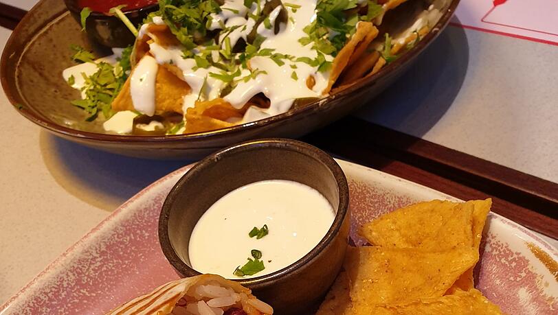 Der Burrito und hinten die Nachos mit viel Soße. Der Burrito und hinten die Nachos mit viel Soße.