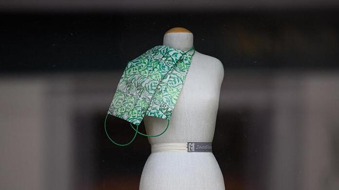 Eine nur noch mit Mund-und Nasenschutzmasken bestückte Puppe im Schaufenster eines Modeladens.