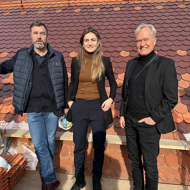 Architekt Florian Nagler, Projektleiterin Sabrina Sommer und Generalkonservator Mathias Pfeil vor dem neu gedeckten Dach. Im Hintergrund ist das Muster gut zu erkennen.
