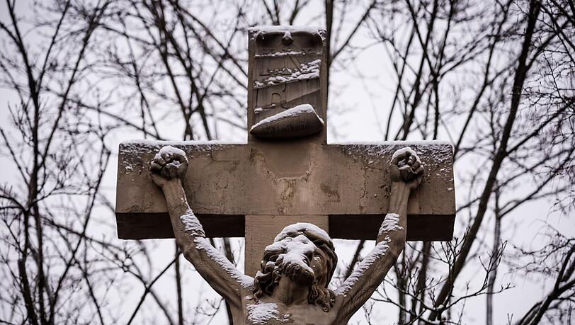 Eine Figur von Jesus am Kreuz ist mit Schnee bedeckt.