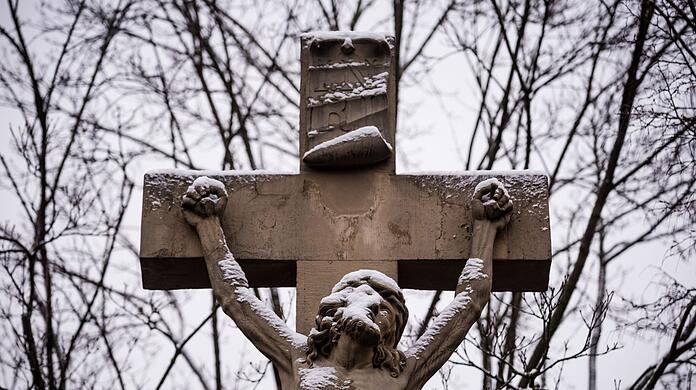 Eine Figur von Jesus am Kreuz ist mit Schnee bedeckt.