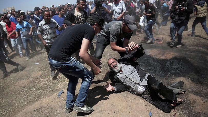 Palästinenser helfen einem Verletzten bei Auseinandersetzungen mit israelischen Truppen an der Grenze zwischen dem Gazastreifen und Israel.