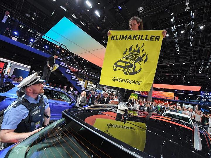 Eine Greenpeace-Aktivistin protestiert am Stand von Volkswagen mit einem Transparent.