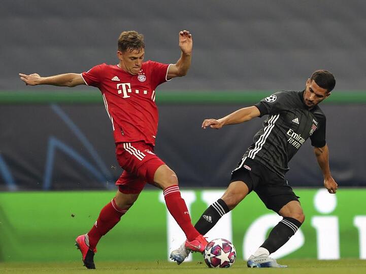 Bayerns Joshua Kimmich (l) kämpft gegen Houssem Aouar von Olympique Lyon um den Ball.
