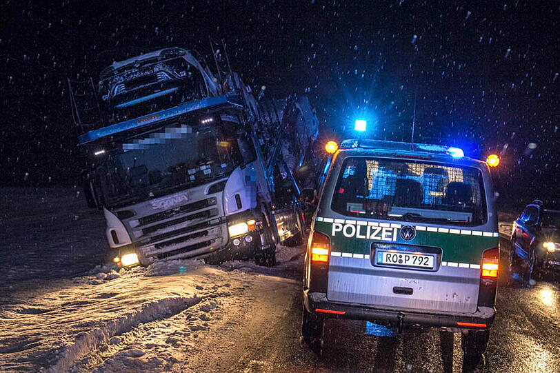 Ein Autotransporter rutscht aufgrund der schneeglatten Fahrbahn in den Graben