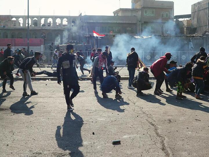 Demonstranten in Bagdad gehen vor Tränengasgeschossen in Deckung.