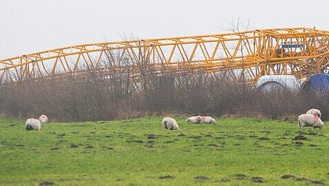 Ein umgekippter Kran liegt auf einer Baustelle für Windkraftanlagen in Janneby (Schleswig-Holstein) neben den Segmenten eines Windrads.