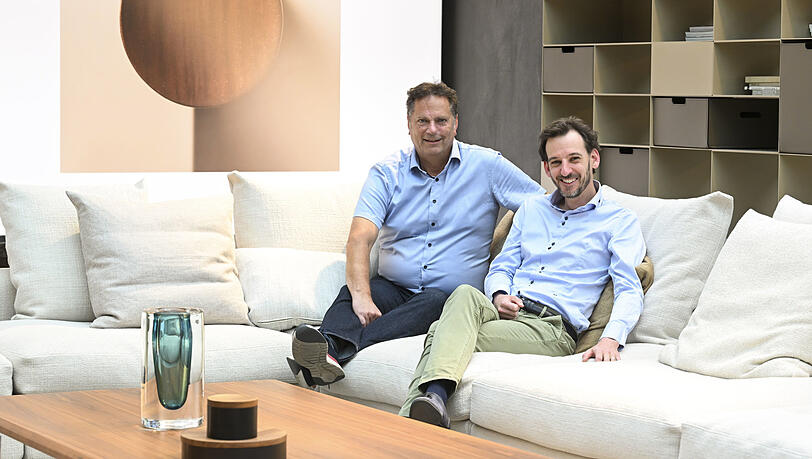 Thomas Böhmler (60) und sein Neffe Matthias Böhmler (39) führen das Einrichtungshaus im Tal in der vierten und fünften Generation. Das riesige Sofa, auf dem die beiden sitzen  – und von dem auf dem Bild nur etwa ein Fünftel zu sehen ist – kostet über 30.000 Euro.